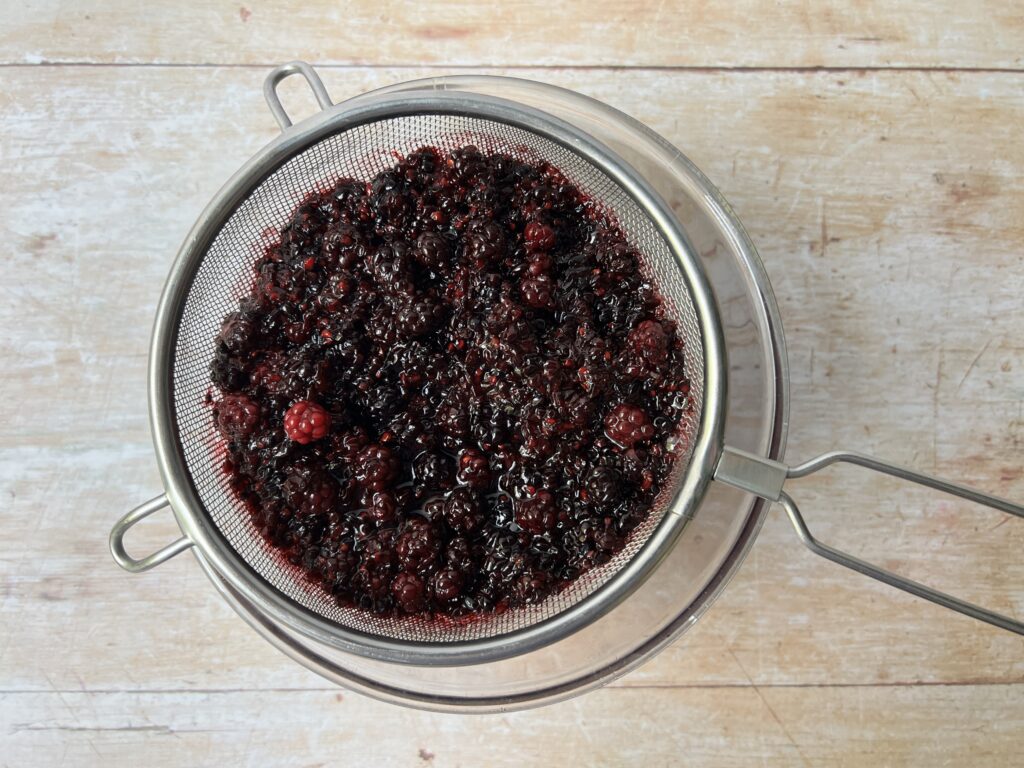 straining bramble shrub mixture through a sieve